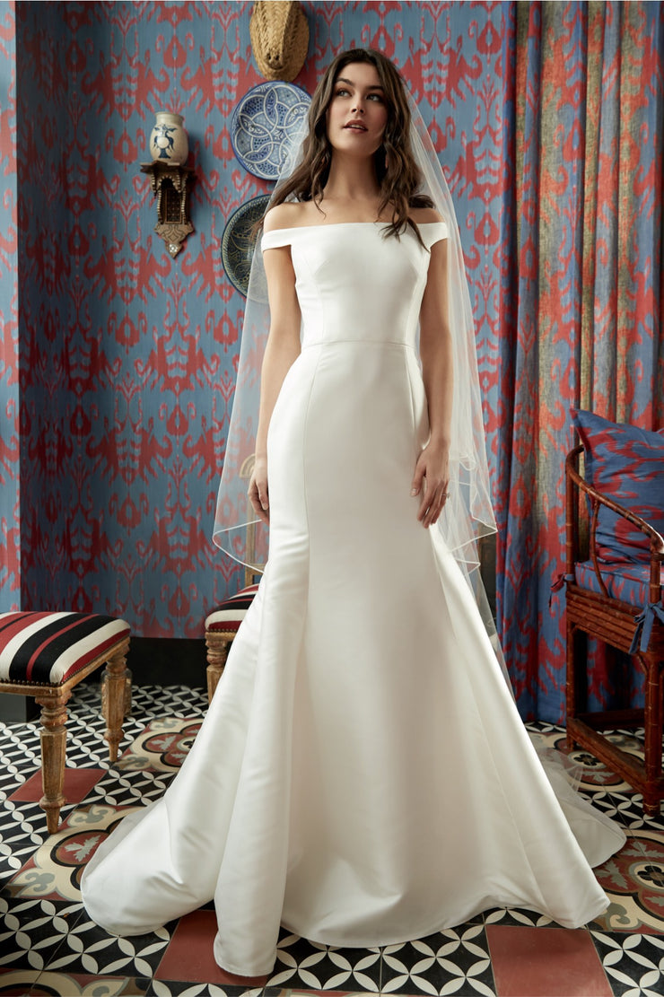 Wtoo by Watters This Mikado gown boasts a streamlined fit and flare silhouette and is paired with an oh-so-romantic “kiss the shoulder” sleeve detailing. With fabric-covered buttons cascading down the back, you cannot help but fall for this modern classic.